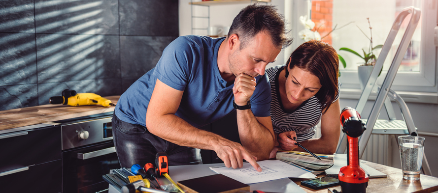 Couple looking at blueprints during kitchen renovation