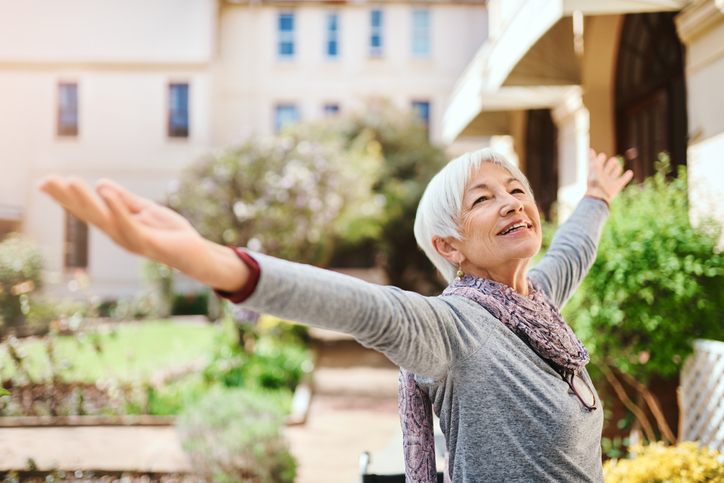 Senior Woman Smiling and Looking Up While Raising Her Hands in the Air