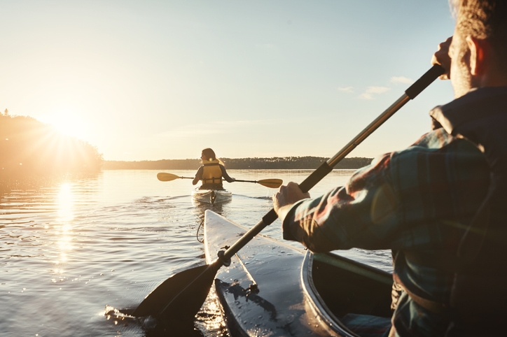 Man and woman kayaking in the lake and admiring the sunrise