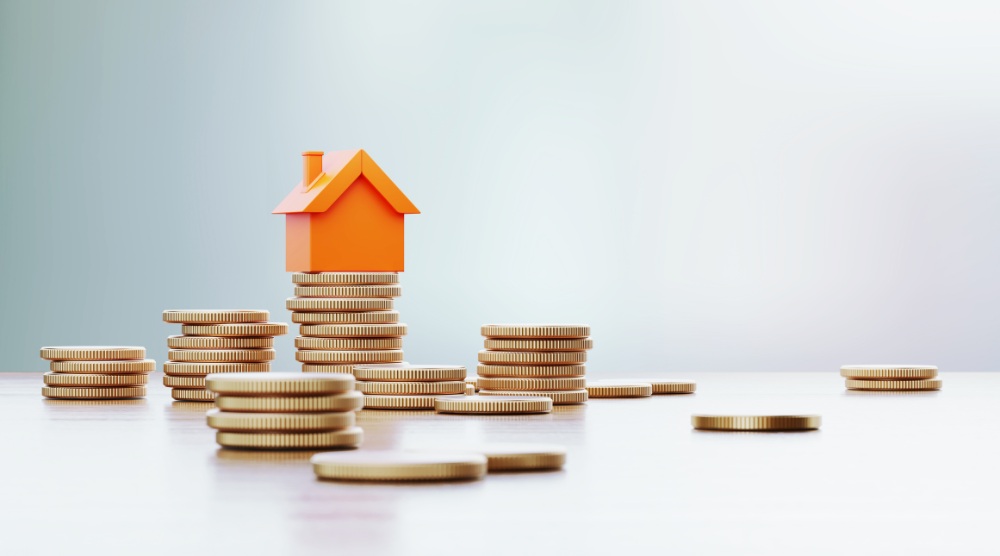 Orange Colored Toy House Sitting over Coin Stacks