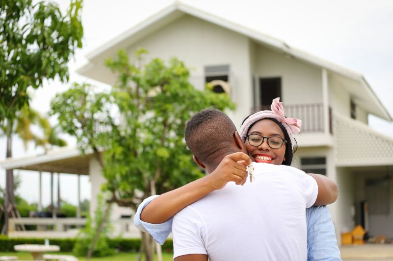 african american wife hugging her husband in front of the house they just move