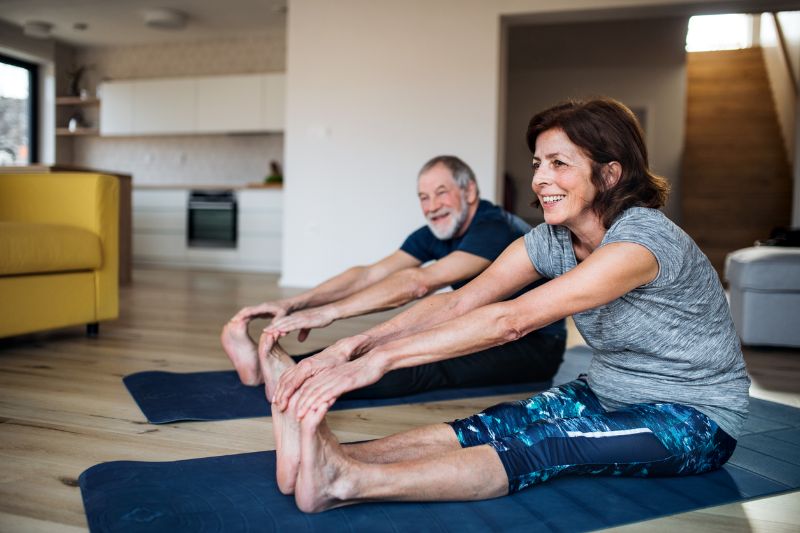 a senior couple indoors at home doing exercise on the floor