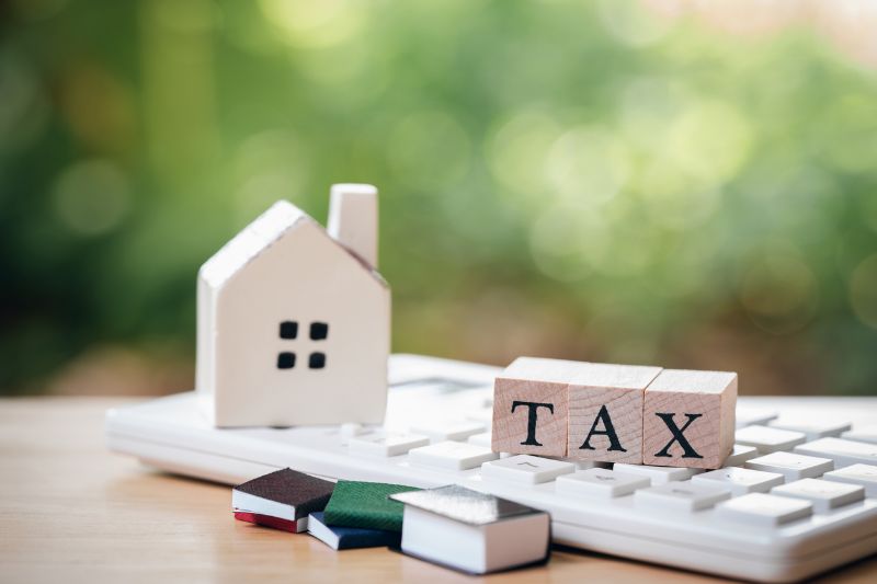 a house model is placed on wood word tax as background